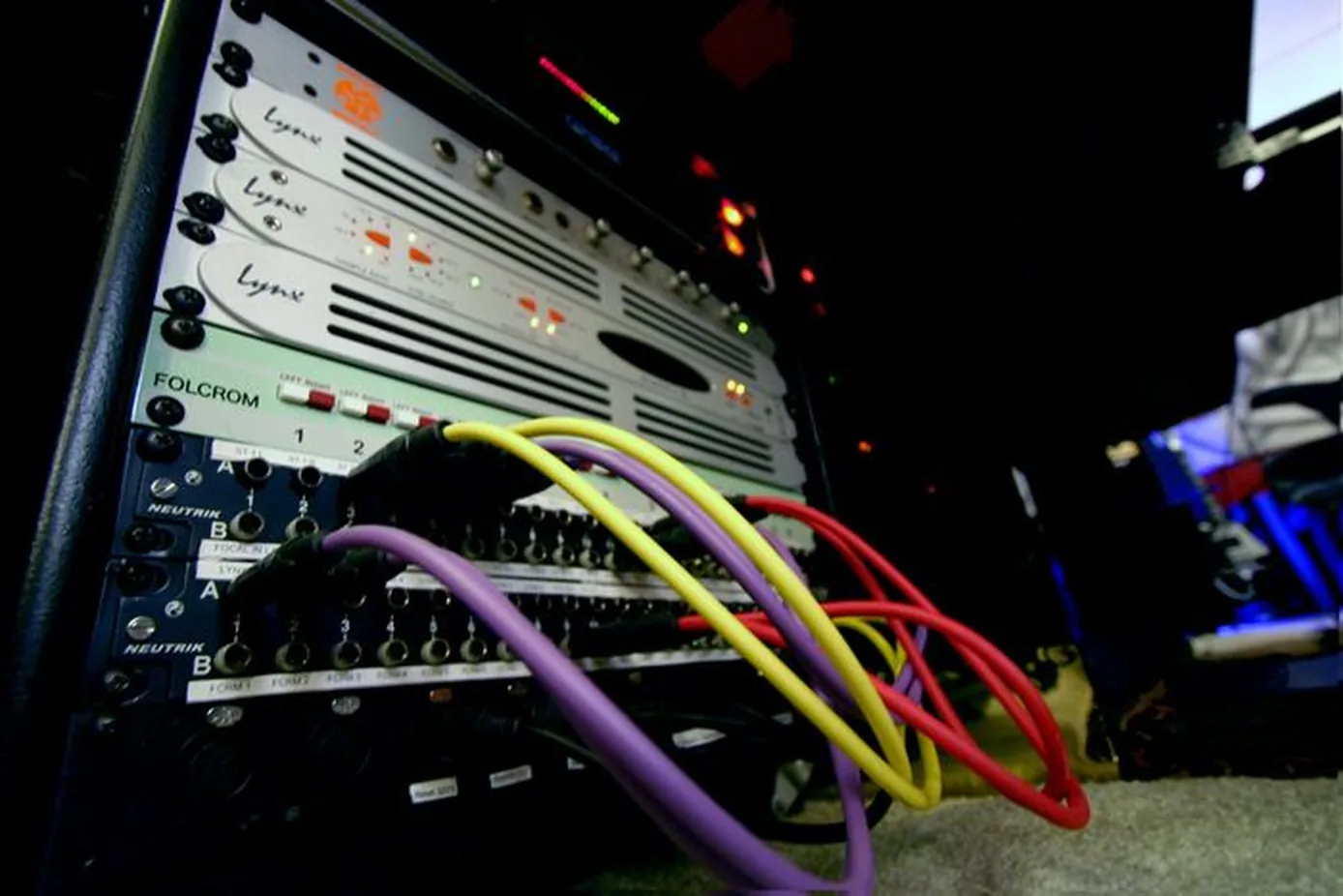 Photo: a studio patchbay in use — coloured patch cables through Neutrik jacks, routing a Folcrom summing mixer and Lynx converters